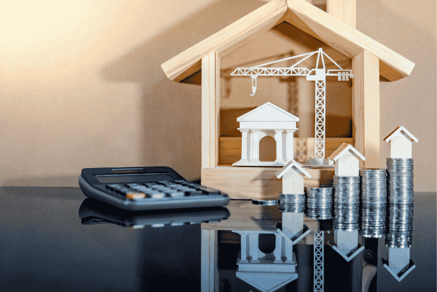 Modèle de maison en bois avec pièces empilées, grue de chantier et calculatrice, symbolisant l’éligibilité au prêt à taux zéro selon la zone et les revenus.