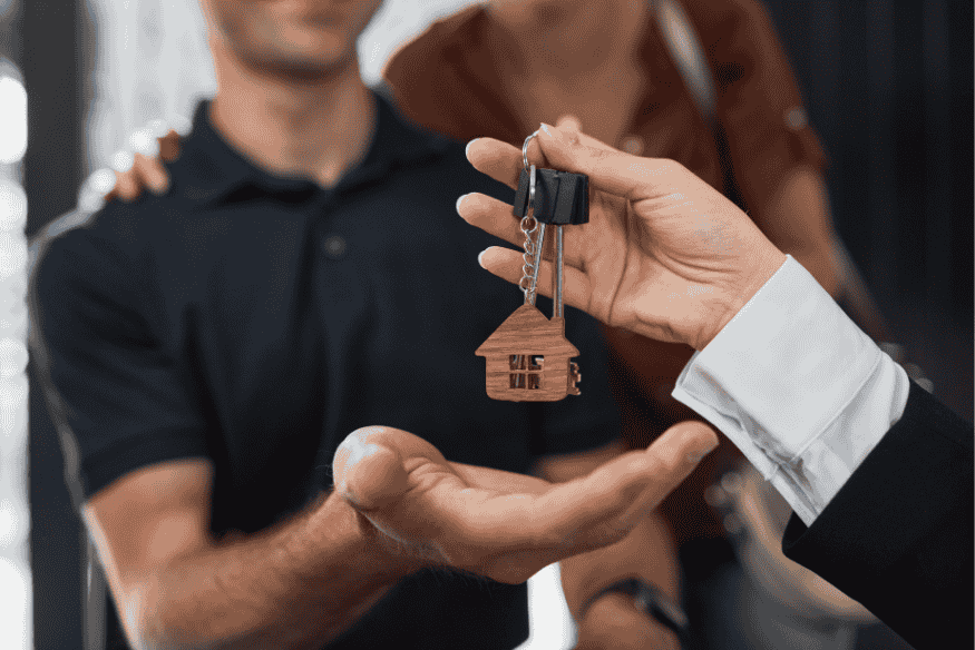 Remise de clés à un jeune couple, symbolisant l’accession à la propriété facilitée par un prêt à taux zéro.