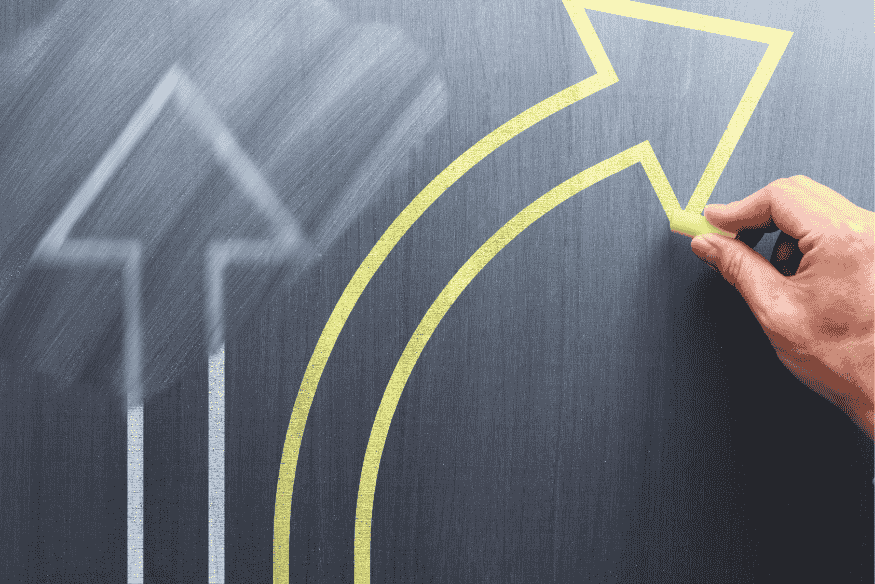 Main traçant une flèche jaune ascendante sur un tableau, symbolisant la relance d’un projet de prêt auprès d’un nouvel établissement bancaire.