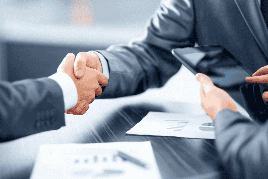 Poignée de main entre deux professionnels en costume après un accord financier, symbolisant la relance réussie d’un projet de prêt.